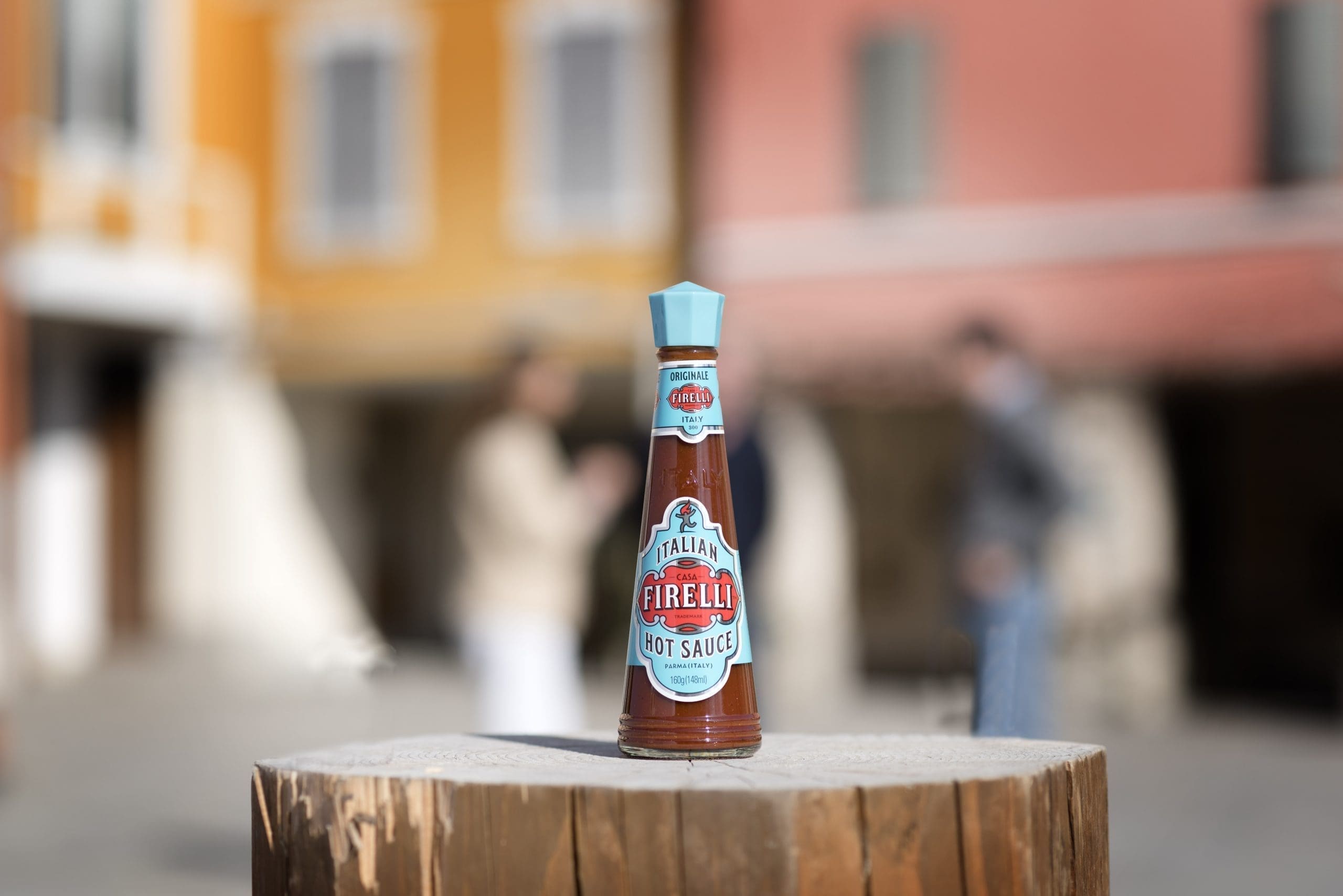 a bottle of firelli hot sauce on a tree stump