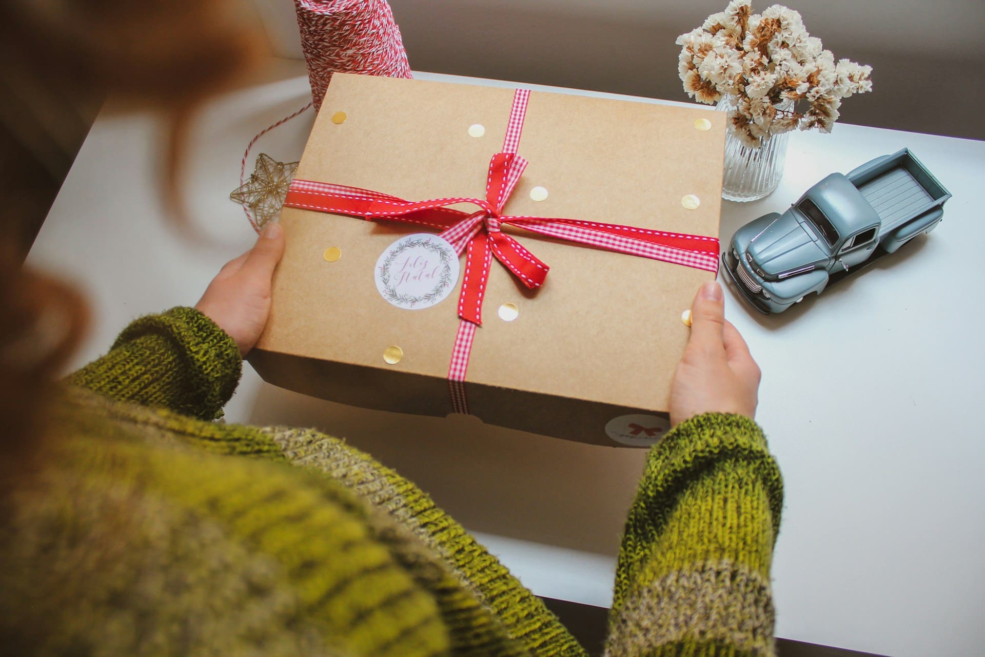 Someone holding a gift box with a ribbon tied around it