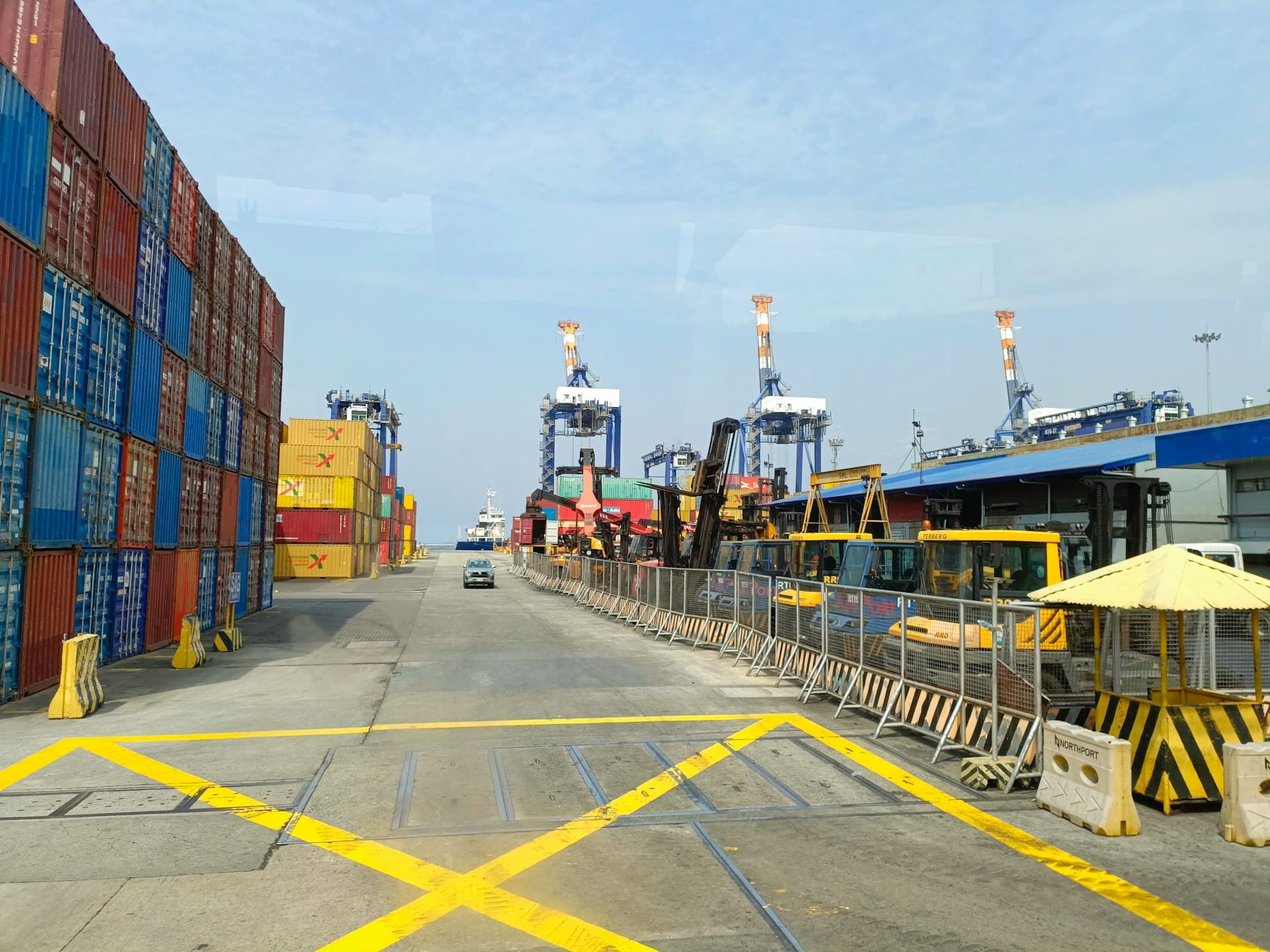 A line of containers with the ocean in the background showing ships that brought the containers over
